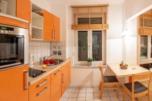 a kitchen with orange cabinets and a small table at Gemütliches kleines Apartment in Dresden