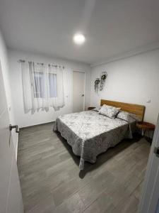 a white bedroom with a bed and a wooden floor at piso en pleno centro in San Fernando