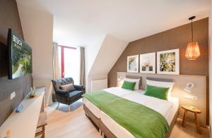 a bedroom with a large bed and a chair at BEECH Resort Plauer See in Plau am See