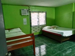 a green room with two beds and a window at Bella's Beach Resort (A) in Bauang