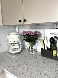 a kitchen counter with a vase of purple flowers and a toaster at Bright & Cozy, Renovated Studio in the Lahti Center in Lahti