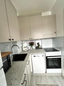 a kitchen with white cabinets and a sink at Bright & Cozy, Renovated Studio in the Lahti Center in Lahti