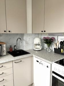 a kitchen with white cabinets and a sink at Bright & Cozy, Renovated Studio in the Lahti Center in Lahti