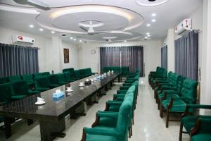 einen Konferenzraum mit einem langen Tisch und grünen Stühlen in der Unterkunft SWAT HOTEL in Mingora
