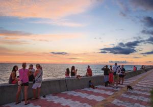 un grupo de personas de pie en un muelle cerca del agua en Blue Steak Wonder Chatan en Chatan