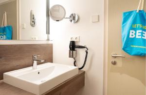 a bathroom with a sink and a phone at BEECH Resort Plauer See in Plau am See