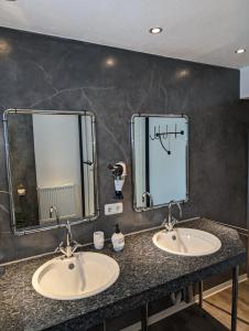 two sinks in a bathroom with two mirrors at Ferienwohnung Zum Kühlen Grund in Eimelrod