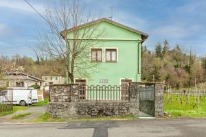 une maison verte avec une clôture en pierre devant elle dans l'établissement Ca' Graziosi Fiori, à Bagnone