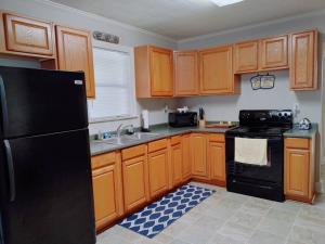 a kitchen with wooden cabinets and a black refrigerator at Quiet Country Small Family Home 5 minutes from town in Mansura