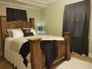 a bedroom with a large wooden bed with black curtains at Quiet Country Small Family Home 5 minutes from town in Mansura
