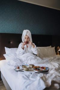 una mujer acostada en la cama con un plato de comida en Holiday Inn Lübeck, an IHG Hotel, en Lübeck