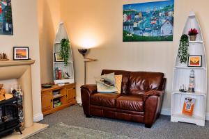 a living room with a brown leather couch and a tv at Finest Retreats - Byron Street in Amble