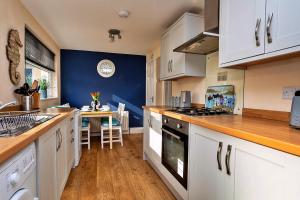 a kitchen with white cabinets and a blue wall at Finest Retreats - Byron Street in Amble
