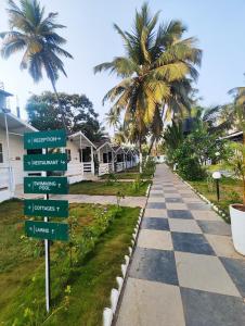 a street sign in front of a house with palm trees at Seawood Beachfront Resort in Morjim