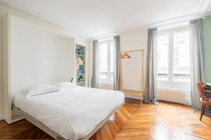 a bedroom with a white bed and a wooden floor at Veeve - Chic By Bonne-Nouvelle in Paris