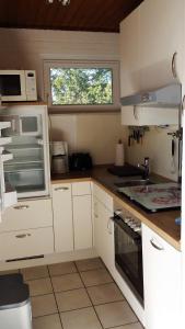 a small kitchen with white cabinets and a window at Bungalow 5566 in Tossens in Butjadingen OT Tossens