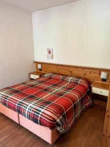 a bedroom with a bed with a plaid blanket at Hotel Culmine in Ardenno