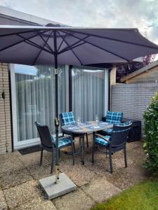 a table with chairs and an umbrella on a patio at Bungalow 5566 in Tossens in Butjadingen OT Tossens