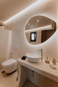 a white bathroom with a sink and a mirror at ONYM Curated Villas in Plaka
