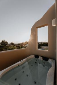a bath tub in a room with a window at ONYM Curated Villas in Plaka