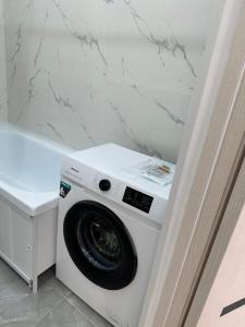 una lavatrice e asciugatrice in un bagno accanto a un bancone di Квартира ad Aqtau