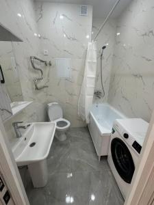 e bagno bianco con lavandino, servizi igienici e vasca. di Квартира ad Aqtau