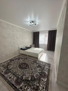 een woonkamer met een bed en een tapijt bij Квартира in Aqtau