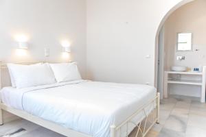 a white bedroom with a large bed with white pillows at Golden Sand in Plaka