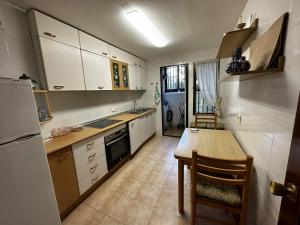 eine Küche mit weißen Schränken, einem Tisch und einem Kühlschrank in der Unterkunft PV34, Apartamento cerca mar con piscina parking in Villajoyosa