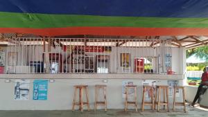 un bar con cuatro taburetes delante en BM. Beach hotel at Nansio, Ukerewe island, en Hamukoko