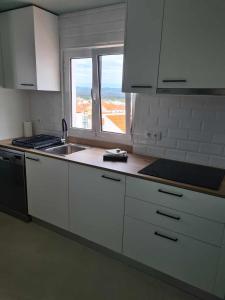 a kitchen with white cabinets and a sink and a window at Casa Limo in São Martinho do Porto