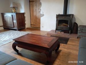 a living room with a wooden coffee table and a stove at Roseland, retraite calme en pleine nature in Saint-Girons +8 photos