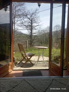 una puerta de cristal con una mesa y una silla al aire libre en Roseland, retraite calme en pleine nature en Saint-Girons