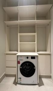 lavadora y secadora en una habitación con estanterías en قمه الفخامه بلكونه Luxury Apartments with balcony, en Riad