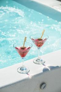 two wine glasses sitting next to a swimming pool at Golden Sand in Plaka