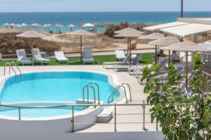 een zwembad met stoelen en parasols en de oceaan bij Golden Sand in Plaka