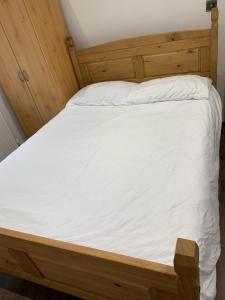 a bed with a wooden frame and white sheets at Private room, renovated with large size white desk In SE9 6PG in London