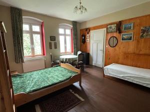 a bedroom with two beds and a table and windows at Dom pod Orlimi Skałami - blisko Zamku Czocha i Jeziora Leśniańskiego in Leśna