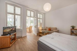 - une chambre avec un lit, une télévision et un canapé dans l'établissement Apartment Martha 3, à Heringsdorf