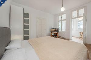 - une chambre blanche avec un lit et une télévision dans l'établissement Apartment Martha 3, à Heringsdorf