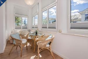 ein Esszimmer mit einem Tisch, Stühlen und Fenstern in der Unterkunft Apartment Martha 3 in Heringsdorf