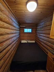 Habitación pequeña con 1 cama en una cabaña de madera en Kuikkoniemi- A Lake view cabin with hot tub n more, en Mikkeli