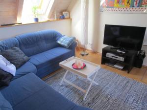 ein Wohnzimmer mit einem blauen Sofa und einem Tisch in der Unterkunft Studio für 2 Personen ca 75 qm in Bessenbach, Bayern Franken in Straßbessenbach