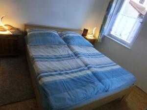 ein Bett mit einer blauen und weißen Bettdecke und einem Fenster in der Unterkunft Wohnung in Schönberg in Lauf an der Pegnitz