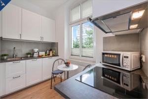 een keuken met witte kasten en een tafel met een magnetron bij Apartment Martha 2 in Heringsdorf
