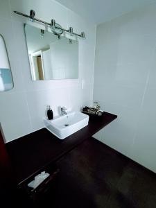 Baño blanco con lavabo y espejo en Room in Guest room - Comfortable single room with shared bathroom and kitchen, en Forbach