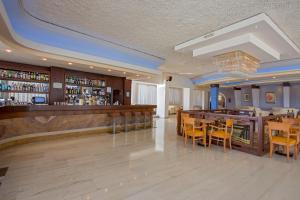 un restaurante con bar, mesas y sillas en Atlantis Hotel en Cos