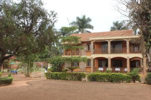 an old house in a park with trees at Cool Breeze Hotel in Jinja
