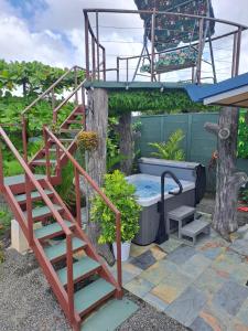 a hot tub and stairs in a garden with a tree at House Monstera Arenal in Agua Azul