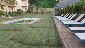 a row of lounge chairs next to a swimming pool at Galini Eden in Agia Marina Nea Kydonias